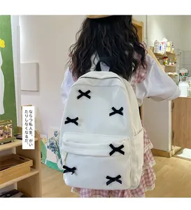 Detailed back view of white corduroy backpack with black ribbon bow tie decorations