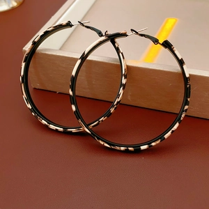 Close-up of leopard print and black leather hoop earrings on a warm metallic tray