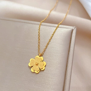 Detailed close-up of a gold titanium steel necklace with a frosted four-leaf clover pendant