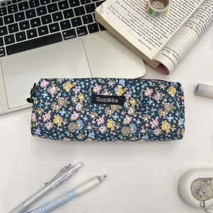 Detailed top view of a floral canvas stationery pouch on a desk with a notebook
