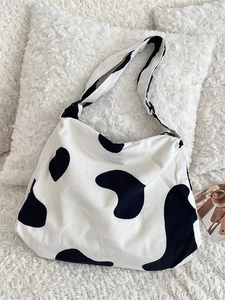 Large corduroy cow print tote bag with black and white patterns on plush background