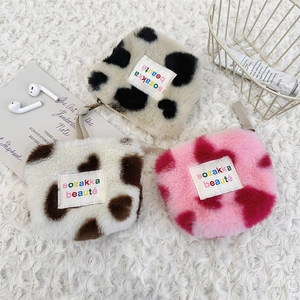 Detail of plush heart coin purses in cow and pink patterns with woven logo label
