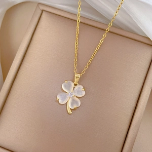 Detailed macro of gold clover necklace with white cat eye stone and center crystal
