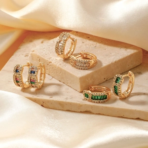 Vintage-Goldcreolen mit Smaragd und bunten Zirkonia auf Seidenhintergrund