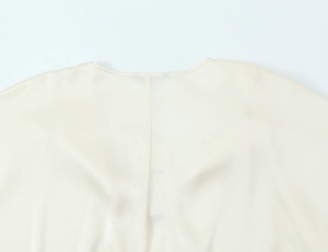 Detailed close-up of cream satin shirt showing collar stitching and silk texture