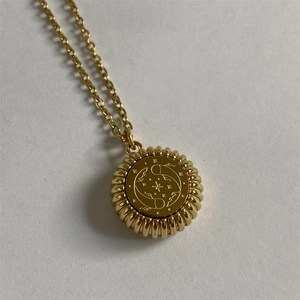 Macro detail of gold Pisces zodiac coin pendant with vintage ribbed edge and stars