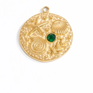 Macro view of gold seashell pendant with a central green gemstone and embossed coral