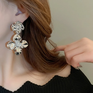 Detailed close-up of large silver floral earrings with textured petals on female model