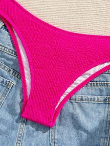 Detail of rose red high-stretch seersucker bikini bottom on denim and knit props