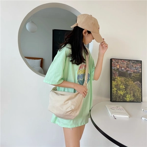 Dettaglio di una borsa a tracolla beige abbinata a una maglietta oversize verde menta