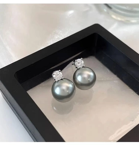 Detail of grey pearl earrings with sparkling diamond studs on white silk fabric