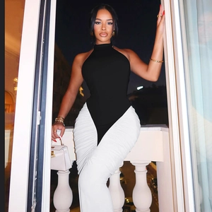 Detail of a chic black halter bodysuit paired with elegant white pleated wide-leg trousers