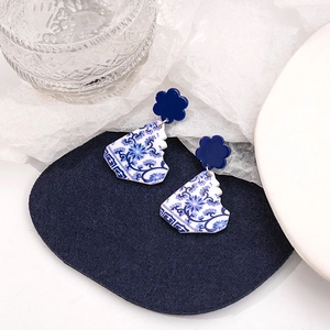Detail of blue floral porcelain earrings on a velvet display with elegant lighting