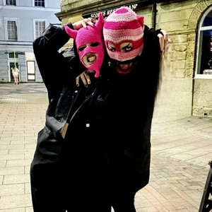 Detail of pink handmade crochet balaclava with devil horns and striped knit mask