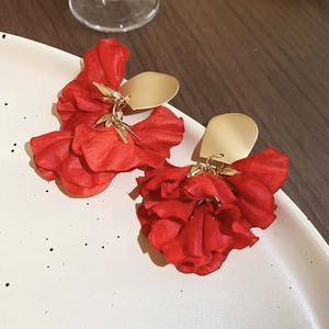 Macro detail of red layered fabric flower earrings with gold finish oval studs