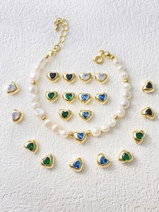 Macro shot of 18k gold plated heart-shaped charms and pearls for DIY jewelry making