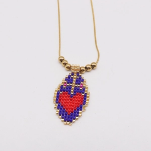 Close-up of handmade beaded heart pendant on a gold snake chain with bead accents
