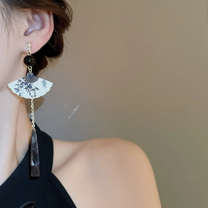 Détail de boucles d'oreilles en forme d'éventail avec motifs de bambou et pendentifs gris