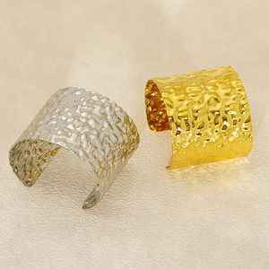 Close-up of wide stainless steel bangles with irregular hammered texture in gold and silver