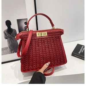 Detail of red woven texture handbag with luxury gold hardware lock and handle