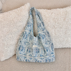 Detailed close-up of blue lace floral embroidery on a soft canvas shoulder bag