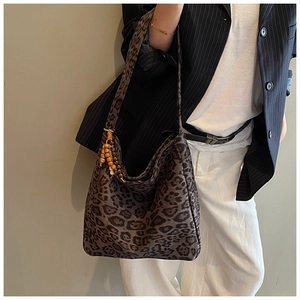 Detail of leopard print tote bag featuring retro wooden bead charms on the shoulder strap