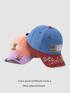 Close-up of cute cartoon bear patches and detailed embroidery on colorful kids baseball caps