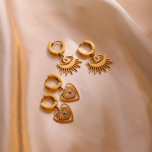 Vintage gold hollow evil eye and heart geometric earrings on champagne silk fabric