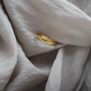 Macro shot of 18K gold plated minimalist ring with engraved crescent moon on light fabric