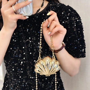 Golden shell-shaped metal handbag with beaded chain strap worn by a model
