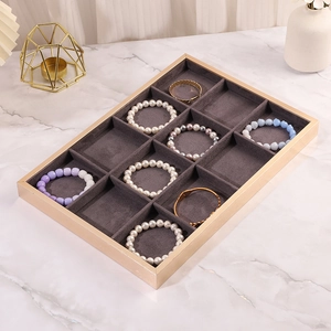 Detail of 12-slot jewelry display tray with gold metal frame and dark grey velvet lining