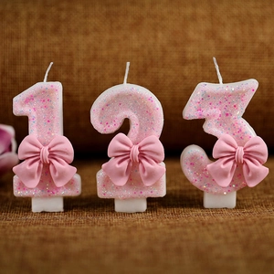 Pink glitter birthday candles with cute ribbon bows featuring numbers one two and three