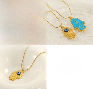 Macro view of gold Hamsa hand necklace with blue evil eye detail and stainless steel chain