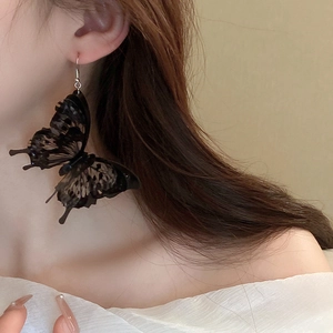 Close-up of black acrylic butterfly hook earrings worn by a model in dark gothic style