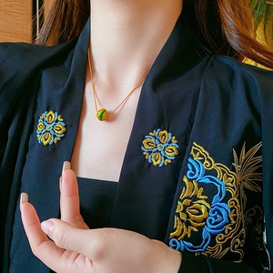 Dettaglio della collana placcata oro 18K con ciondolo in smalto verde indossata da modella