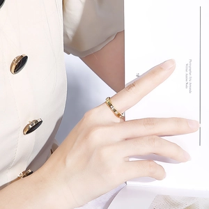 Close-up of 18k rose gold Roman numeral ring with diamonds worn on female finger