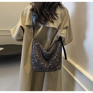 Model wearing a large leopard print tote bag with a beige coat in a minimalist room