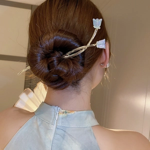 Gros plan de l'épingle à cheveux tulipe bleu clair avec tige argentée dans un chignon