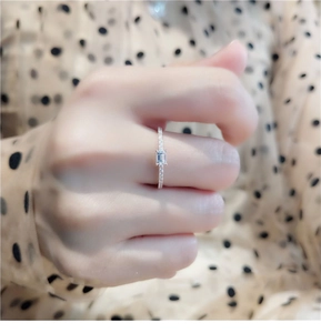 Detailed view of silver-plated emerald cut cubic zirconia ring with pavé band on hand