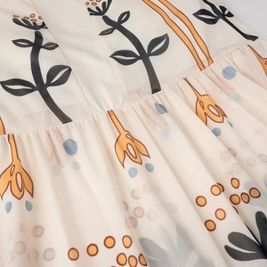 Detailed close-up of beige mesh fabric featuring floral prints and delicate pleating