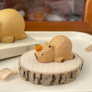 Close-up of wooden capybara ornament with an orange on head placed on a natural wood stump