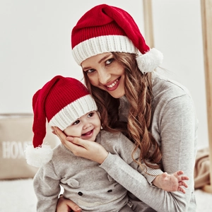 Matching red and white knitted Christmas hats with faux fur pom-poms for mother and baby
