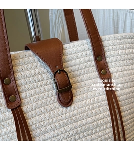Detail of white woven tote bag featuring brown leather strap and vintage metal rivets