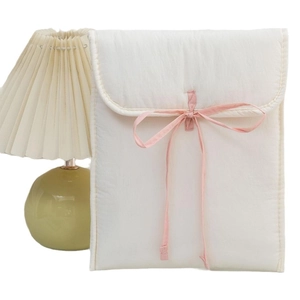 Quilted cream 13-inch laptop sleeve with pink ribbon bow on a minimalist white background