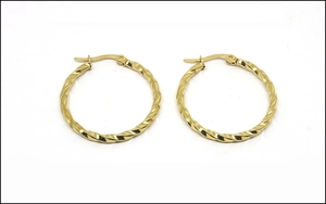 Macro detail of gold-plated twisted rope texture on large stainless steel hoop earrings
