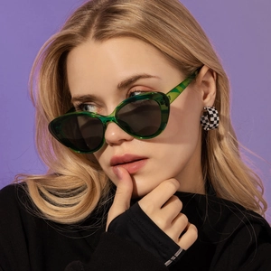 Stylish translucent green cat-eye sunglasses and checkerboard earrings on female model