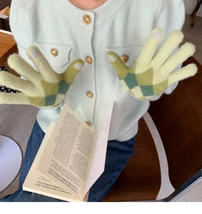 Detail of green and yellow diamond pattern knit gloves on hands for winter warmth