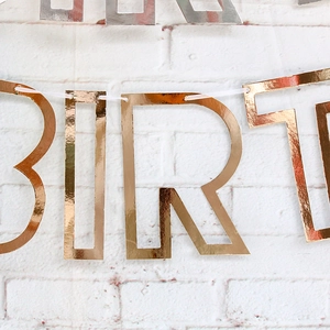 Close-up of rose gold Happy Birthday banner letters with reflective metallic foil finish