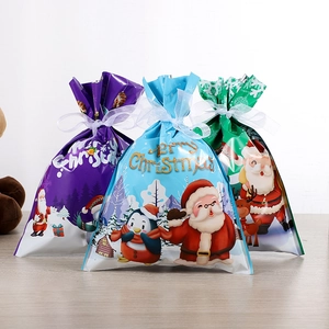 Détail de sacs cadeaux de Noël à cordon en violet, bleu et vert avec Père Noël