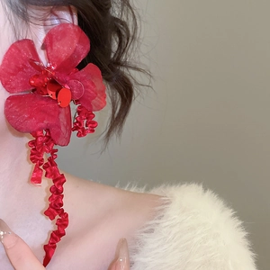 Close-up of red fabric flower earrings with long ribbon tassels on a model